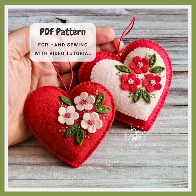 May include: Two heart-shaped felt ornaments. One is red with white flowers and green leaves, the other is white with red flowers and green leaves. The text "PDF Pattern For Hand Sewing With Video Tutorial" is in a white box.