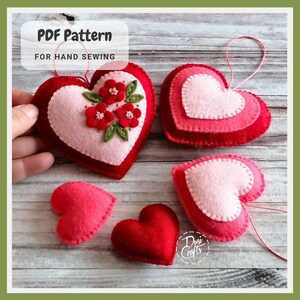 May include: Handmade felt heart ornaments in shades of red and pink. Some hearts are layered, others feature floral embellishments. The text "PDF Pattern For Hand Sewing" is visible. These ornaments are perfect for Valentine's Day or other special occasions.