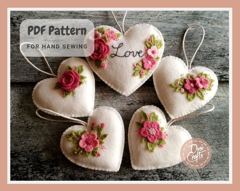 May include: Five white felt heart ornaments with pink and green embroidered flowers and the word "Love" on one heart.