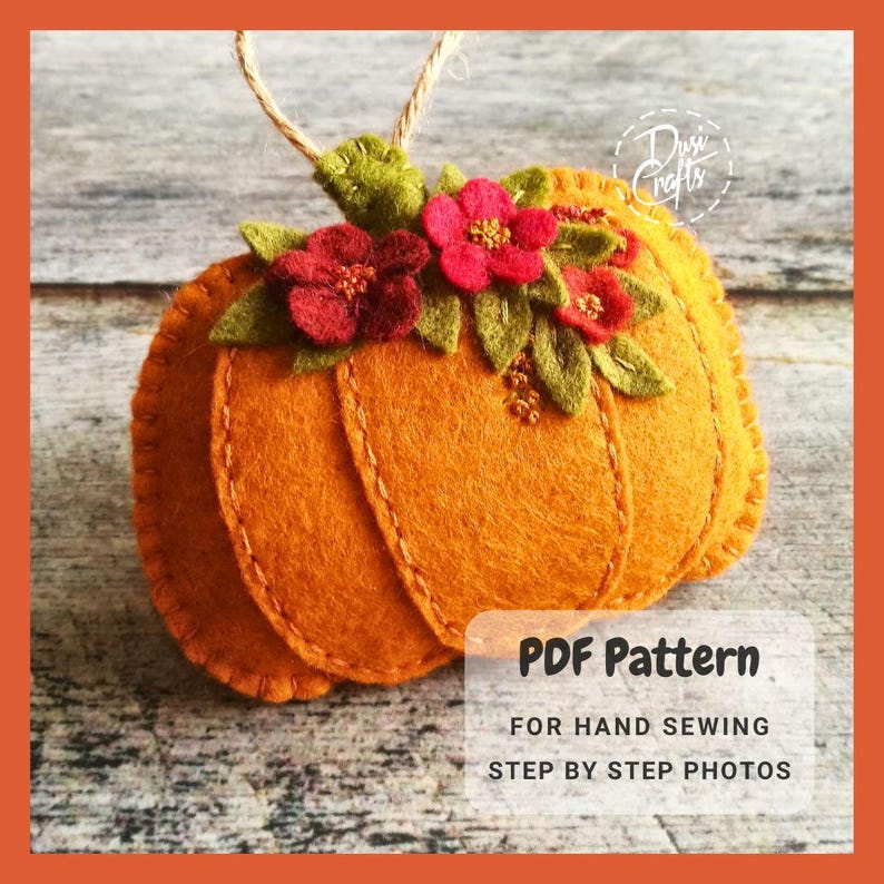 May include: A felt pumpkin ornament with a stem and green leaves. The pumpkin is decorated with red felt flowers and has a stitched design. The ornament is on a wooden surface. PDF Pattern for Hand Sewing Step by Step Photos.
