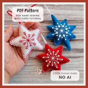 May include: Three star-shaped felt ornaments in white, blue, and red, each featuring embroidered snowflake patterns and white ribbon loops. The white star has red stitching, while the blue and red stars have white stitching and small beads.