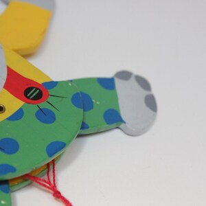 Puede incluir: Un t&iacute;tere de madera de un animal gris con lunares azules, verdes, amarillos y rojos. El t&iacute;tere tiene una cuerda atada a su cabeza.