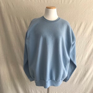 May include: A light blue sweatshirt with a crew neck and long sleeves.