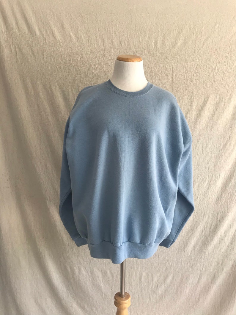 May include: A light blue sweatshirt with a crew neck and long sleeves.