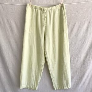 Puede incluir: Pantalón de lino verde claro con cintura de cordón y dos bolsillos. El pantalón está colgado en un tendedero.
