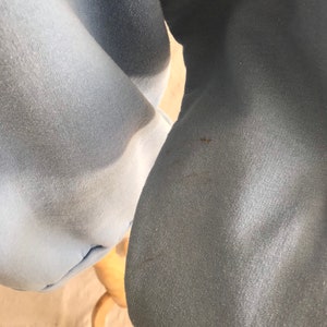 May include: Close-up of a light blue sweatshirt with a darker blue hue on the sleeve. The fabric has a soft, textured appearance.