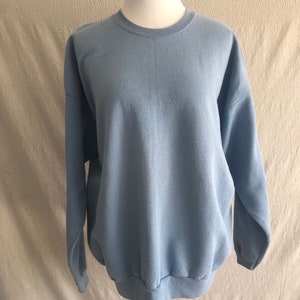 May include: A light blue sweatshirt with a crew neck and long sleeves.