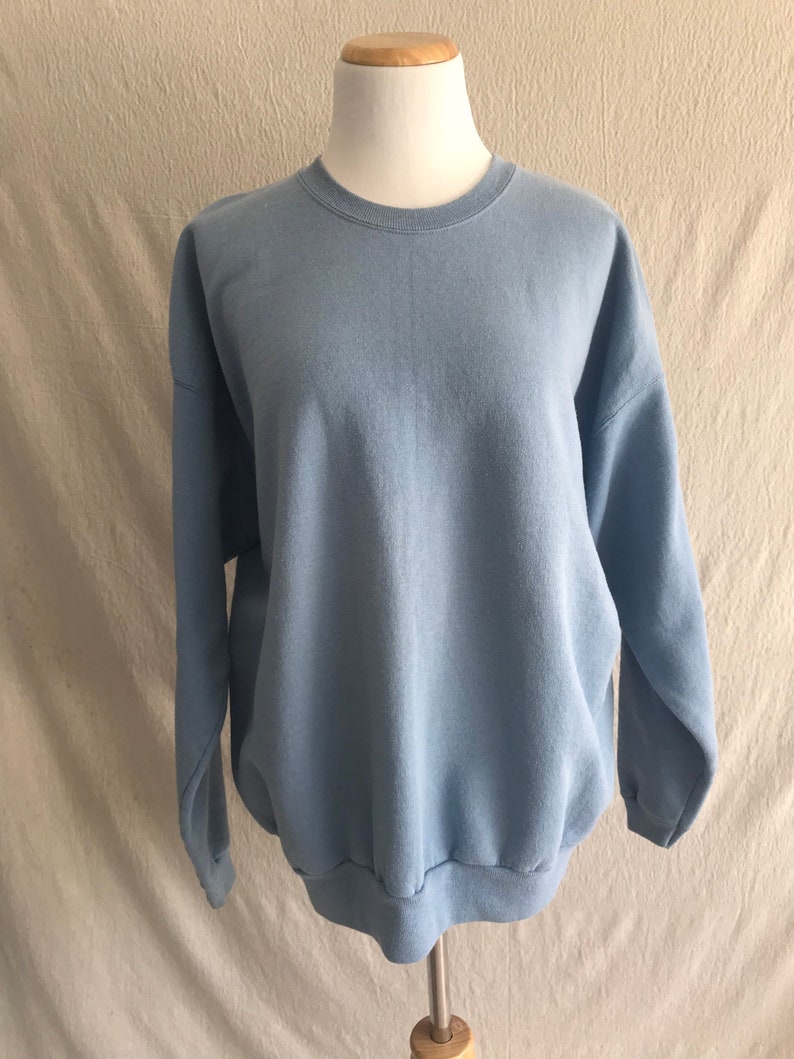 May include: A light blue sweatshirt with a crew neck and long sleeves.