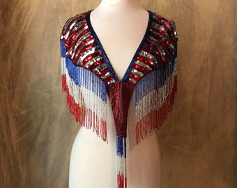 May include: A red, white, and blue sequined shawl with fringe. The shawl is on a white dress form.