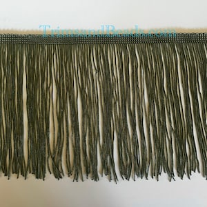 May include: Green fringe trim measuring approximately 2.5 cm wide. The fringe is made from a soft, silky material with a subtle sheen.