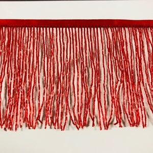 May include: Red beaded fringe trim. The fringe is made of small, red beads that are strung together to create a long, flowing fringe. The fringe is about 1 inch wide and is perfect for adding a touch of glamour to any project.