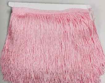 Puede incluir: Borde de flecos rosa con respaldo blanco. Los flecos miden aproximadamente 2,5 cm de largo.