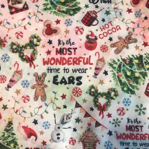 May include: A colorful fabric with a Christmas theme featuring a gingerbread man, a snowman, a Christmas tree, and the text "It's the most wonderful time to wear ears".
