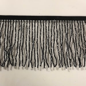 Puede incluir: Borde de flecos de cuentas negras. El fleco está hecho de pequeñas cuentas negras que se ensartan para crear un fleco largo y fluido. El fleco tiene aproximadamente 2,5 cm de ancho y es perfecto para agregar un toque de elegancia a cualquier proyecto.