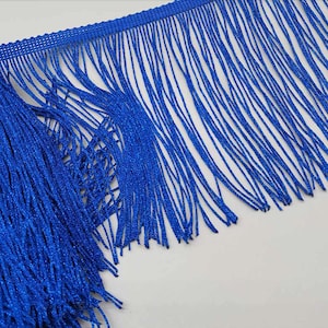 May include: A close-up of a blue fringe trim. The fringe is made of thin, shiny threads.