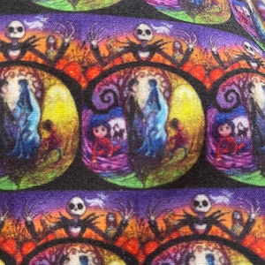 Puede incluir: Tela multicolor con un patrón repetido de círculos que parecen vidrieras con personajes de Pesadilla Antes de Navidad. Cada círculo presenta a Jack Skellington, Sally y Zero. El fondo es morado oscuro con una franja morada clara.