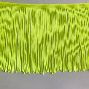 May include: A bright neon green fringe trim with a woven edge. The fringe is approximately 2.5 cm long.