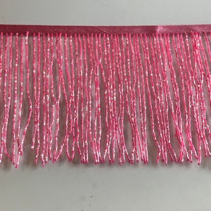 Pode incluir: Franja de contas rosa com suporte de cetim. A franja é feita de pequenas contas redondas que são enfiadas juntas para criar um efeito delicado e fluido.