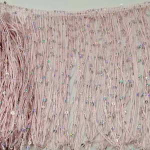 May include: Pink fringe trim with iridescent sequins. The fringe is about 2 inches long.