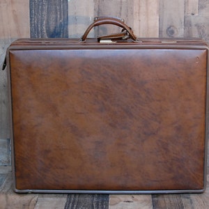 May include: A brown leather suitcase with a metal handle.