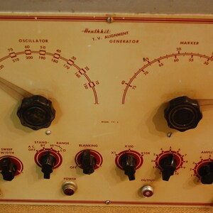 May include: A Heathkit TV Alignment Generator with multiple knobs and dials. The dials are labeled "Oscillator", "Marker", "Hor Phase", "Sweep Width", "Stand By", "Range", "Blanking", "X100", "X10K", "Amplitude", and "Marker Range".