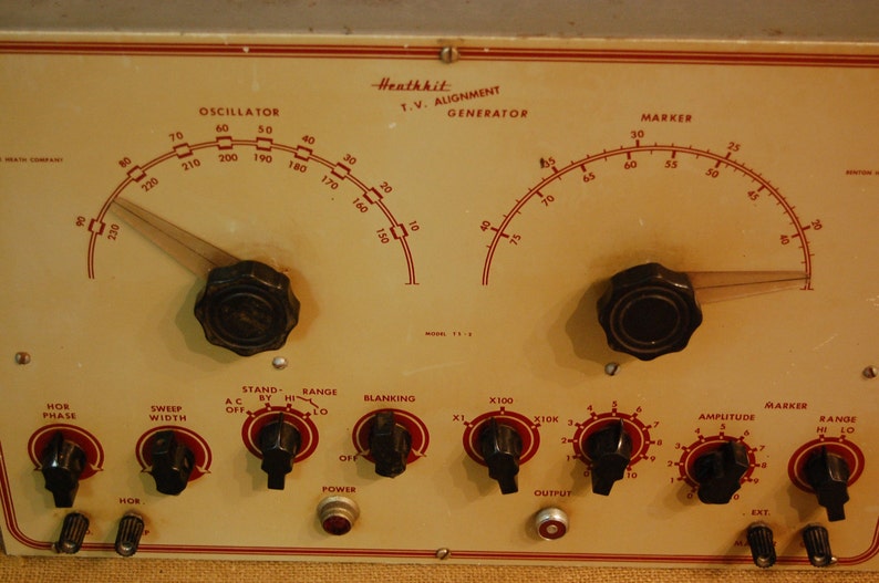May include: A Heathkit TV Alignment Generator with multiple knobs and dials. The dials are labeled "Oscillator", "Marker", "Hor Phase", "Sweep Width", "Stand By", "Range", "Blanking", "X100", "X10K", "Amplitude", and "Marker Range".