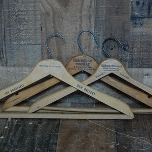 Puede incluir: Tres perchas de madera con ganchos de metal. Las perchas est&aacute;n etiquetadas con "The Roosevelt", "The Pride of the South" y "New Orleans". La percha del medio tiene una etiqueta que dice "Hennessy Cognac, A Friend For Life".