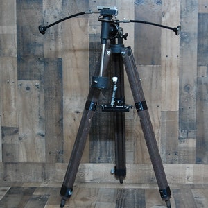 May include: A black tripod with a wooden base and a black metal telescope mount. The tripod has three legs and is adjustable in height. The telescope mount is attached to the top of the tripod and has a black metal arm that extends out to the side. The arm is used to adjust the angle of the telescope.