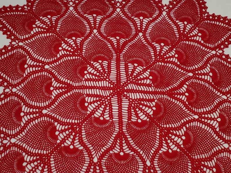 May include: A red crocheted table runner with a delicate, intricate pattern of overlapping circles and swirls.