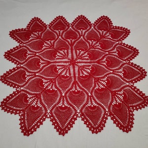 May include: A red crocheted table runner with a delicate, intricate design featuring a repeating pattern of leaves.