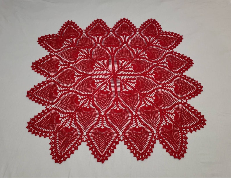 May include: A red crocheted table runner with a delicate, intricate design featuring a repeating pattern of leaves.
