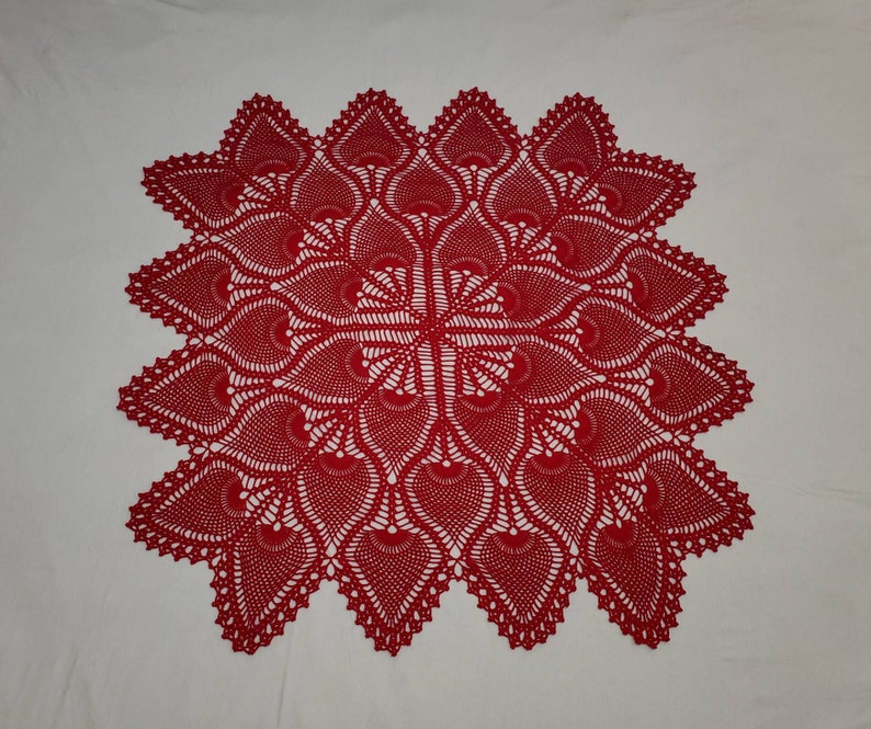 May include: A red crocheted doily with a delicate, intricate design. The doily is circular and features a central motif surrounded by repeating patterns.