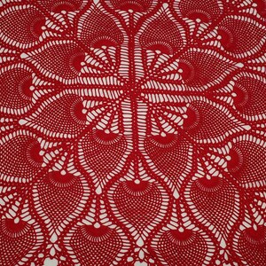 May include: Red crocheted doily with a delicate, intricate pattern. The doily features a circular design with a central motif and radiating spokes.