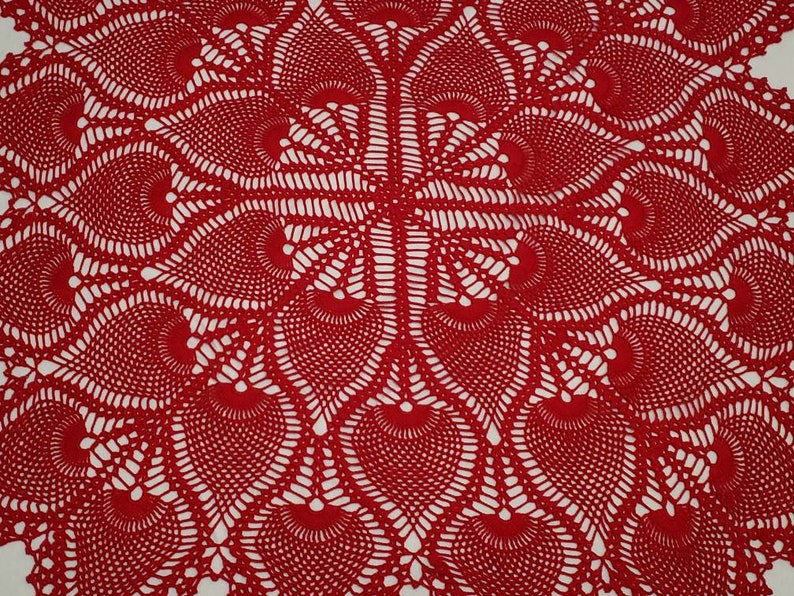 May include: Red crocheted doily with a delicate, intricate pattern. The doily features a circular design with a central motif and radiating spokes.