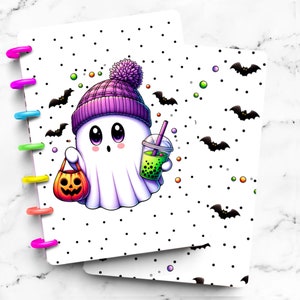 May include: A Halloween-themed planner cover featuring a cartoon ghost wearing a purple beanie and holding a pumpkin-shaped candy bag and a boba drink. The cover has a white background with black polka dots and bat illustrations. The planner rings are multi-colored.