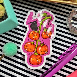 Puede incluir: Una pegatina con una ilustraci&oacute;n de dibujos animados de tomates en una vid, cada uno con un cigarrillo. Un p&aacute;jaro negro se posa en la vid. La pegatina tiene un borde rosa y est&aacute; sobre un fondo a rayas blancas y negras.