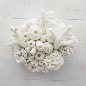 May include: A white crocheted coral reef wall decor with different shapes and textures. The coral is made of yarn and is a realistic representation of coral found in the ocean.