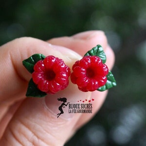May include: A pair of red raspberry earrings with green leaves. The earrings are made of polymer clay and are about 1 inch in diameter.