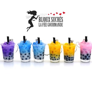 Può includere: Una fila di mini tazze di bubble tea in vari colori, tra cui viola, blu, giallo e rosa. Ogni tazza ha una cannuccia nera ed è riempita di perle di tapioca scure. Le tazze sono disposte su uno sfondo bianco.