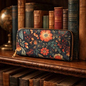 May include: A floral print wallet with a gold zipper. The wallet features a dark background with orange, red, and green floral patterns. The wallet is rectangular and appears to be made of fabric.