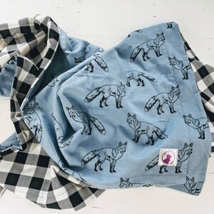 May include: A blue and white checkered baby blanket with a blue fabric side featuring a repeating pattern of black fox silhouettes.