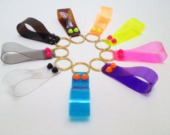 May include: A set of ten colorful keychains with clear plastic straps and gold metal rings. Each keychain has two small, colorful plastic beads attached to the strap.