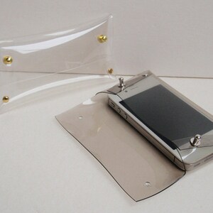 May include: Two clear plastic pouches with gold metal snaps. One pouch is empty and the other contains a smartphone.