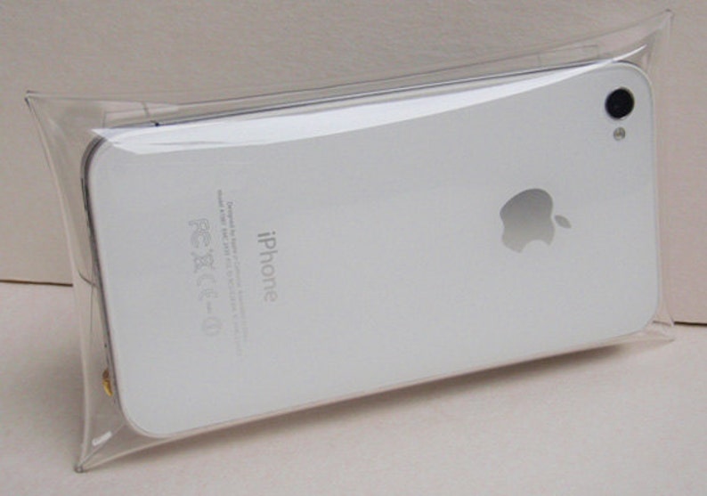 May include: A white iPhone in a clear plastic bag. The back of the phone has the Apple logo and the word "iPhone" printed on it.