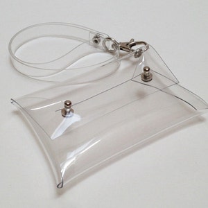 May include: A clear plastic clutch bag with a silver chain strap and silver metal accents. The bag is made of a transparent material, allowing the contents to be visible.