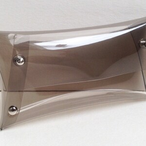 May include: A clear plastic clutch bag with a brown tint and silver metal clasps.