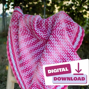 May include: A pink and white crochet blanket with a white border, draped over a wooden easel. The blanket has a geometric pattern and is displayed outdoors on a grassy surface. A digital download button is visible in the lower right corner of the image.