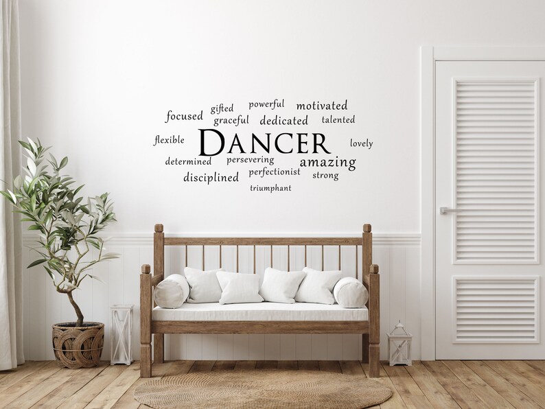 May include: A white wall with a black word cloud that reads "DANCER" surrounded by words describing a dancer, such as "focused", "gifted", "powerful", "motivated", "graceful", "dedicated", "talented", "flexible", "determined", "persevering", "amazing", "disciplined", "perfectionist", "strong", "lovely", and "triumphant".