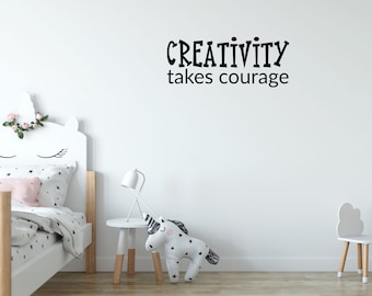 May include: A white wall with black text that reads "CREATIVITY takes courage". The wall is in a child's bedroom with a white bed, a white nightstand, a white lamp, and a white unicorn stuffed animal.