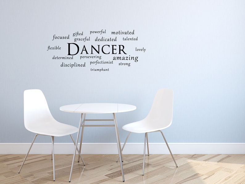 May include: A white table with two white chairs in front of a light blue wall with a black word cloud that says "DANCER" and includes words like "gifted", "powerful", "motivated", "focused", "graceful", "dedicated", "talented", "flexible", "determined", "persevering", "perfectionist", "amazing", "lovely", "strong", "disciplined", and "triumphant".